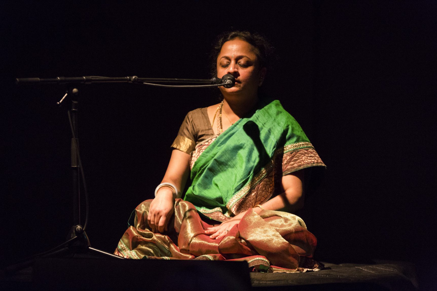 Supriya sat cross-legged, singing into microphone