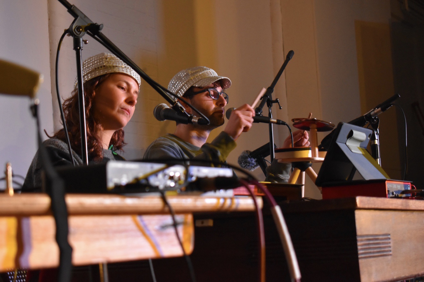 The Fargions perform on stage seated at keys, with microphones, audio interfaces and percussion instruments.