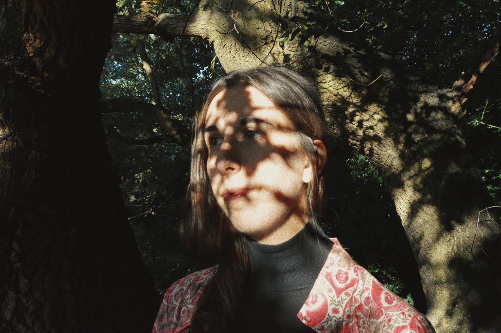 Headshot of Composer Ana Alves standing in front of trees with dappled sunlight on her face.